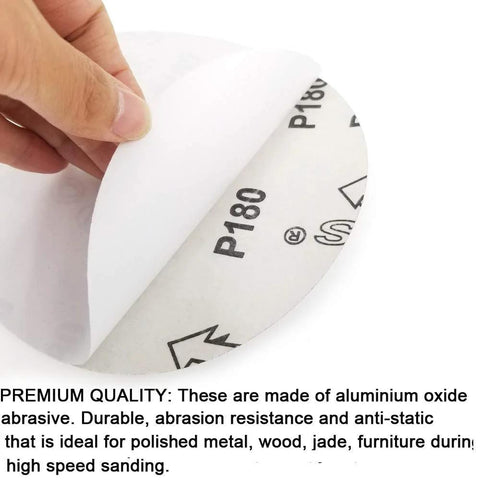 Close-up of a 6-inch PSA sanding disc being peeled from its paper backing; aluminum oxide abrasive, P180 grit.