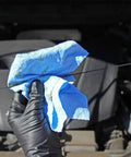 Blue V40 Value Series Center Pull Wiper Sheets being used to clean an engine dipstick, showing oil absorption and durability.