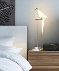Bird Themed Modern Art LED Floor Lamp For Home and Office, tall standing light with PVC shade by a bedside table in bedroom.
