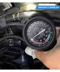 Fuel pump and vacuum tester gauge held in hand inside car engine bay; large black dial with white markings