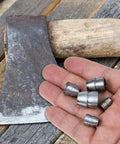Hand holding iron wedges and axe, heavy duty splitting handle metal tapered wedge for axe installation and woodworking.