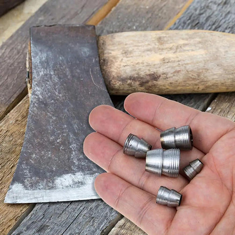 Hand holding iron wedges and axe, heavy duty splitting handle metal tapered wedge for axe installation and woodworking.