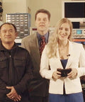 Group of eight people standing in an electronics lab with shelves and equipment in the background.