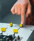 Hand adjusting slider with 5 Pack Universal Yellow Fader Caps For DJ Mixers Replacement Slider Potentiometer Knobs on a console.