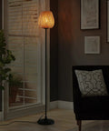 Japanese Style Bamboo Floor Lamp With Handwoven Rattan Shade in living room, tall standing light beside couch, black metal legs.