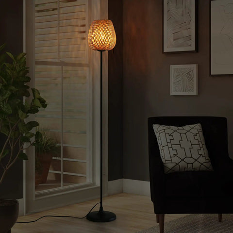 Japanese Style Bamboo Floor Lamp With Handwoven Rattan Shade in living room, tall standing light beside couch, black metal legs.