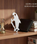 Wallet Sized Stainless Steel Multi Tool Card With Utility Slot And Ruler displayed on a shelf with a wallet and books.