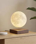 Lit Floating Moon Lamp With Magnetic Levitation And Spinning 5.9 Inch Moon Light on wooden base near plant for room decor.