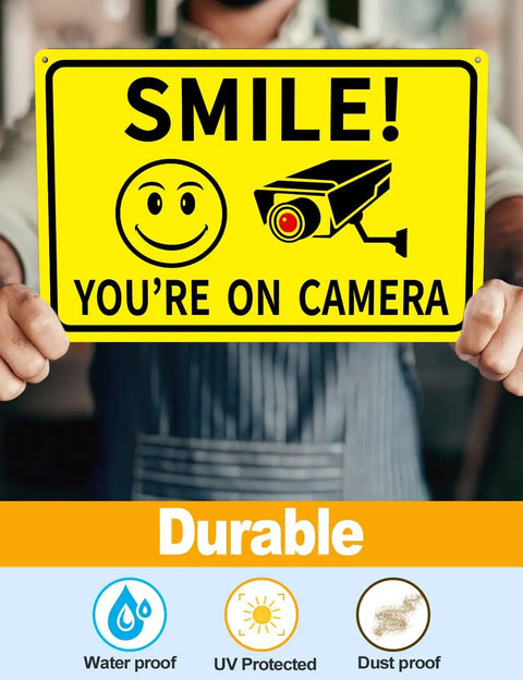 Person holding a Smile You're on Camera sign, 4 Pack Smile Youre On Camera Signs 8x12 Rust Free Aluminum Outdoor Video Surveillance Signs