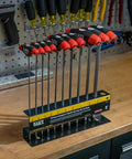 Tough As Nails T-Handle Hex Key Set With Stand, 10-Piece SAE Inch Wrenches displayed on a workbench with tools in the background.