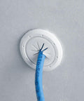Front view of white plastic cable pass-through port (1.5-inch outer / 1-inch inner) installed in wall with blue cable.
