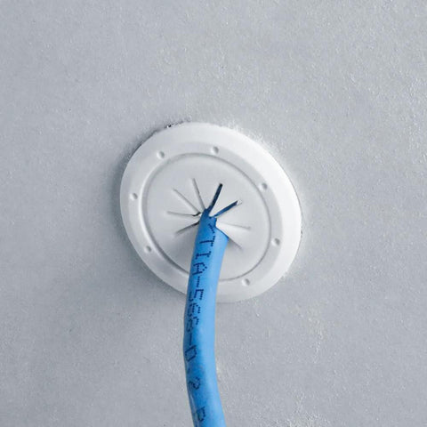 Front view of white plastic cable pass-through port (1.5-inch outer / 1-inch inner) installed in wall with blue cable.