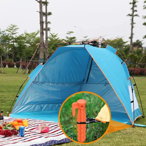 8 Pack Must Have Safety Orange Tent Stakes 8.8 Inch Plastic Anchors holding blue tent on green grass
