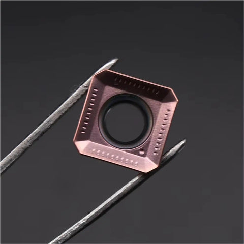 Close-up of Pro Grade Carbide Inserts for CNC Metal Turning Tools, seen held by tweezers, with a focus on cutting edge design.