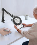 Person reading with 5X And 10X Magnifying Lamp With Stand Clamp Lighted Magnifier For Close Work Crafting Sewing Model Making Jewelry.