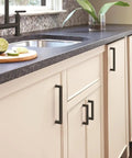 Square Matte Black Cabinet Knobs About An Inch And A Quarter Wide For Kitchen Cabinets on white cabinets near sink.