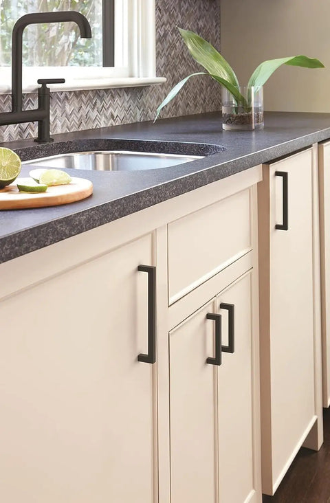 Square Matte Black Cabinet Knobs About An Inch And A Quarter Wide For Kitchen Cabinets on white cabinets near sink.