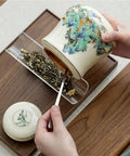 Hand holding Vintage Airtight Ceramic Double Tea Canisters For Loose Leaf Coffee Beans And Spices with a tea scoop.