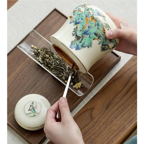 Hand holding Vintage Airtight Ceramic Double Tea Canisters For Loose Leaf Coffee Beans And Spices with a tea scoop.