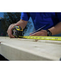 Person using FatMax Auto Lock Tape Measure 25 Ft With 1-1/4 Inch Wide Blade Detachable End Hook Quick Lock For Fast Marking on wood