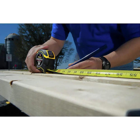 Person using FatMax Auto Lock Tape Measure 25 Ft With 1-1/4 Inch Wide Blade Detachable End Hook Quick Lock For Fast Marking on wood