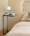 Set Of 2 C Shaped End Tables That Slide Under The Sofa For Easy Laptop Work Or Snack And Drink Tray And TV Tray Space Saving Black Living Room And Bedroom Couch Side Tables in bedroom with lamp and books.