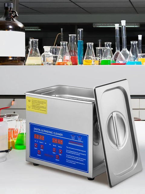 Front view of a stainless steel ultrasonic cleaner with blue digital control panel and open lid on lab bench.