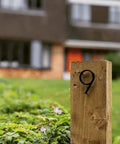 5-inch black stainless steel house number 9 installed on a wooden stake in a yard