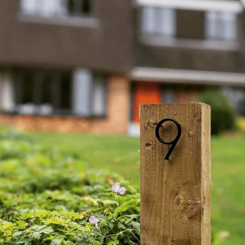 5-inch black stainless steel house number 9 installed on a wooden stake in a yard