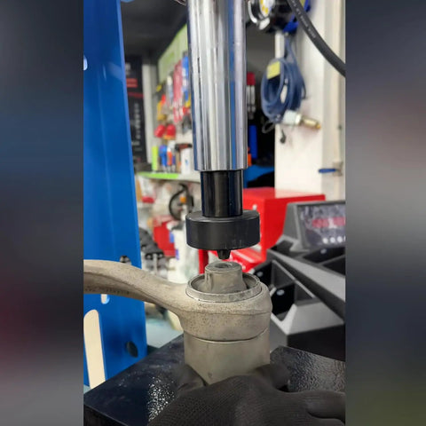 35Pcs Bushing Press Kit For Hydraulic Shop Press in use removing a bearing from a car suspension component.