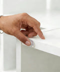 User applying a clear silicone cabinet door bumper from the Straight Up Solid 164 Piece Pack for furniture protection.