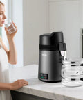Smooth Sippin Water Distiller With Built Tough Stainless Core And Crystal Clear Glass Pot in kitchen with glass of water.