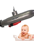 Mini RC Submarine Toy For Bath Time And Pool Play, Realistic Sub Design With Propeller Accessories next to a smiling baby