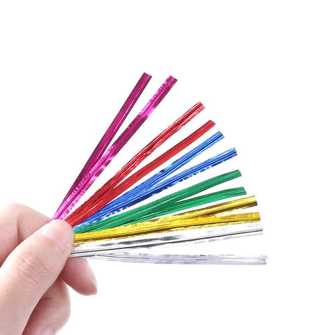 Hand holding colorful metallic twist ties for bread bags, candy, and party decor including silver metallic twist ties 350 yard pack