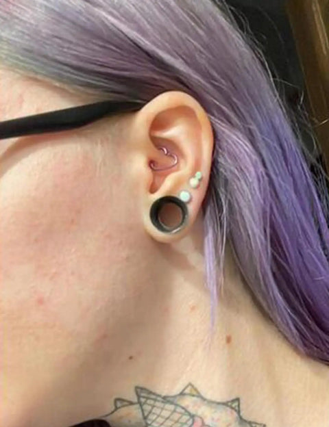 Person wearing 10 Gauge Silicone Ear Gauges Set Ultra Thin Tunnels Plugs For Ear Piercing in left ear with purple hair
