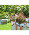 Grab And Go Garden Tool Storage Stool With Detachable Bag And Multiple Pockets Portable Weeding Seat Floral Rose Pattern Rugged Canvas And Jute Build For Easy Outdoor Cleanup showing tools and flowers in garden.