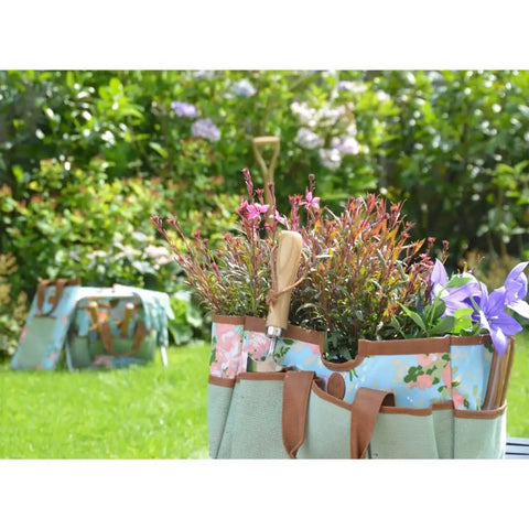 Grab And Go Garden Tool Storage Stool With Detachable Bag And Multiple Pockets Portable Weeding Seat Floral Rose Pattern Rugged Canvas And Jute Build For Easy Outdoor Cleanup showing tools and flowers in garden.