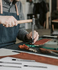 Craftsman using Six Piece Beefy Metal Hollow Hole Punch Kit for leather with tools visible, designed for DIY belt and wallet making