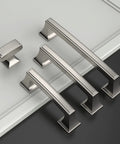 Four stainless steel kitchen cabinet handles of varying sizes displayed on a black and white surface