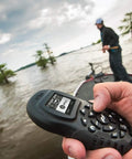 Hand holding Extra Bluetooth I Pilot System Remote For Trolling Motors Second Handheld Controller with LCD screen on a boat