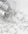Legit Durable Push Pins 600 Count Standard Thumb Tacks With Kickass Steel Points and Clear Rounded Tops spilled from jar.