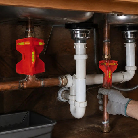 Spirit Level, Foldable Pipe, Fixed Pipe Corner Angle Gauge in use under a sink with copper and PVC pipes.