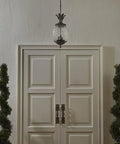 Lanai Collection 3 Light Outdoor Hanging Lantern in Black Coral finish with leaf and flower motifs above white doorway.