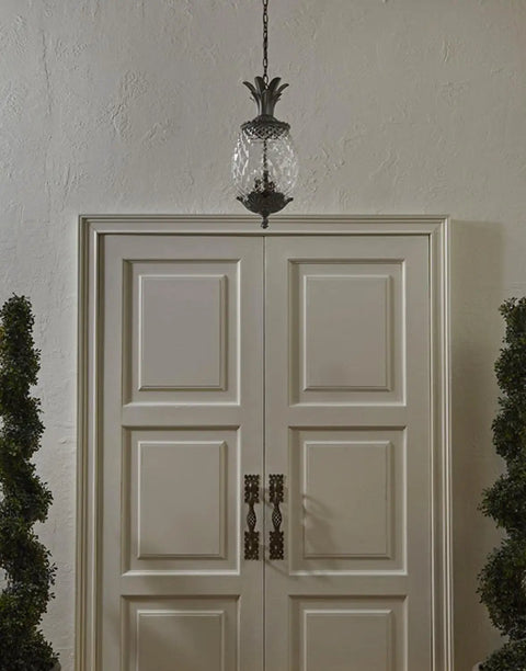 Lanai Collection 3 Light Outdoor Hanging Lantern in Black Coral finish with leaf and flower motifs above white doorway.