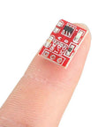 Close-up of a TTP223 capacitive touch switch module on a finger for Arduino projects, 15x11mm size, red PCB, part of Twenty Piece Capacitive Touch Switch Modules TTP223 2.5 To 5.5V Self Lock Or No Lock For Arduino Maker Friendly Touch Button Sensor 15 By 11 Millimeters Plug And Play DIY Projects.