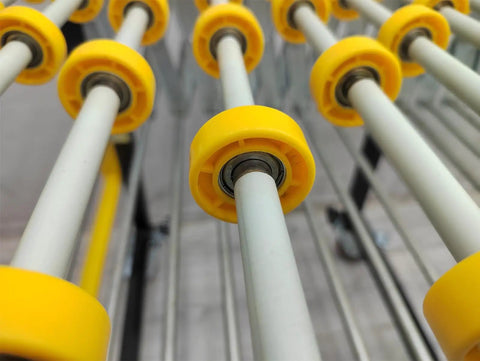 Close-up of yellow rollers on Expandable Roller Conveyor With Adjustable Length And Height For Industrial Use, Stainless Steel Rollers With Wheels.