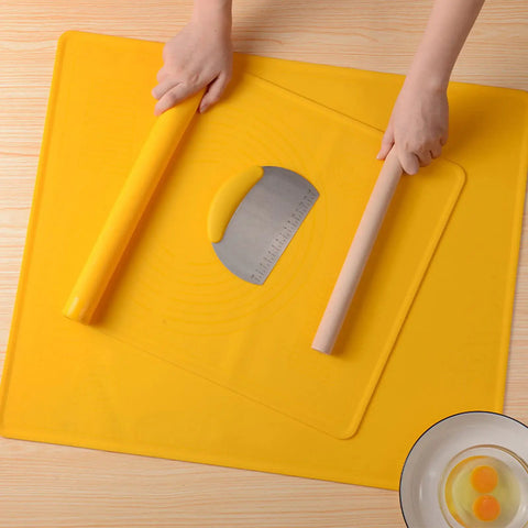 Hands rolling dough on yellow silicone baking mat with pastry cutter and bowl of eggs