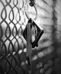 Beefy Heavy Duty Keychain Pry Bar For Everyday Carry hanging on a metal fence, stainless steel minimalist EDC multitool close-up.
