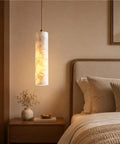Alabaster Pendant Light Natural Marble Long Tube Hanging Lights with Wood Ceiling Canopy Modern Nordic Mini Pendant Lamp for Kitchen Island Bedroom Hallway(25 * 6cm) illuminating a cozy bedroom.