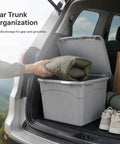 Heavy Duty Stackable Storage Totes With Secure Hinged Lids And Smooth Rolling Casters Plus Reinforced Side Handles For Clutter Free Closet Organization And Dorm Spaces in a car trunk with a green blanket being stored.